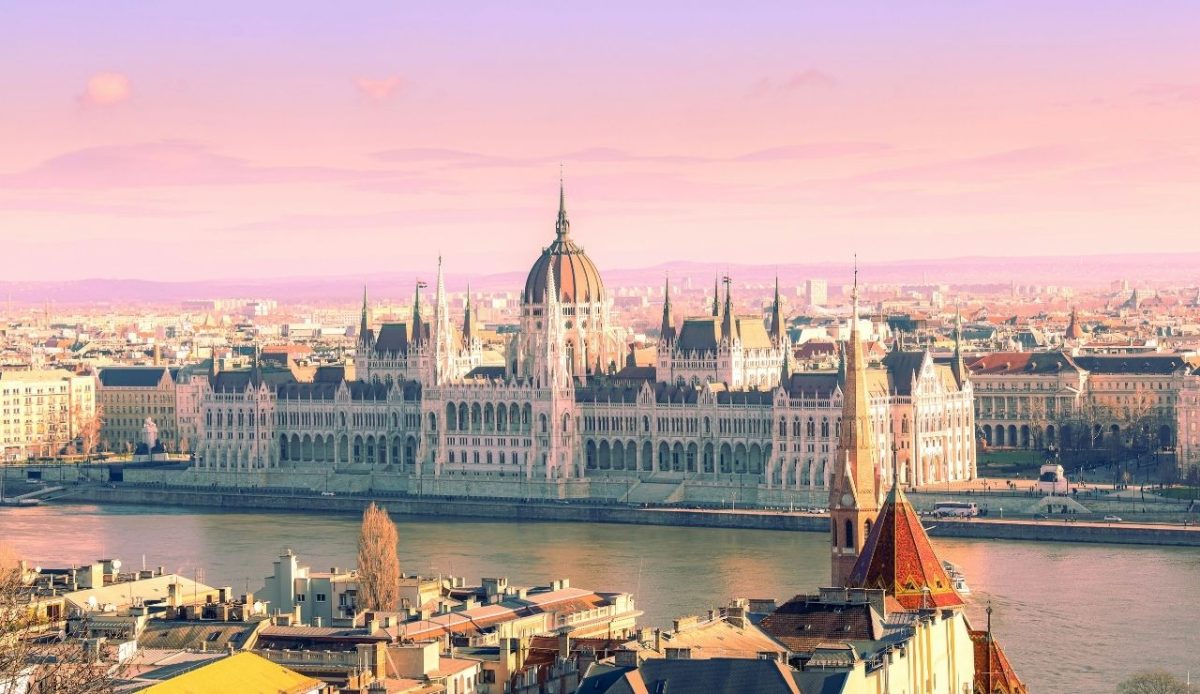Hungarian Parliament Building in Budapest with the Danube River in front at sunset
