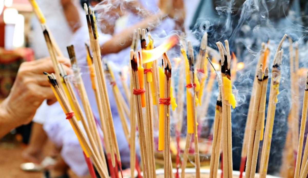 Burning incense sticks with smoke rising during a religious or cultural ritual
