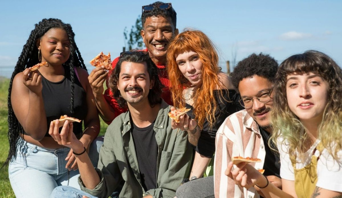 Group of people eating pizza outdoors