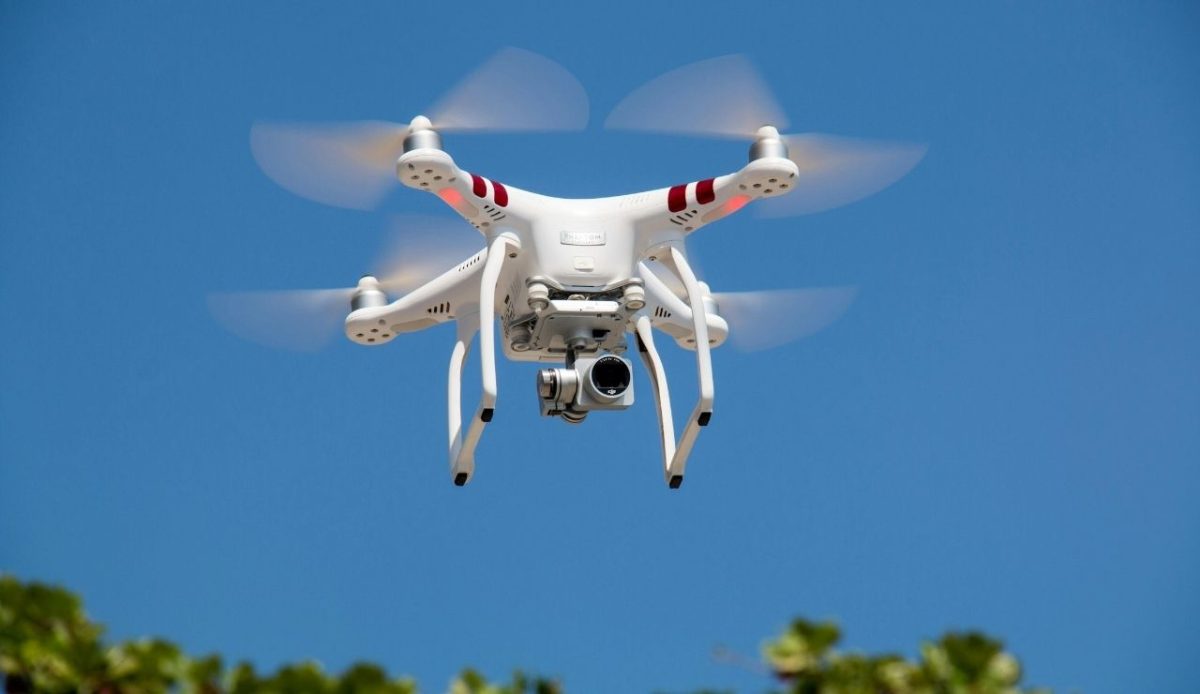 White quadcopter drone with camera flying in the sky during daytime