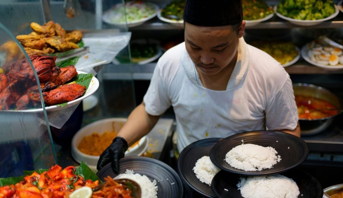9 Travel Habits Quietly Changing How People Explore 7 Street food vendor serving plates of rice with various dishes displayed around