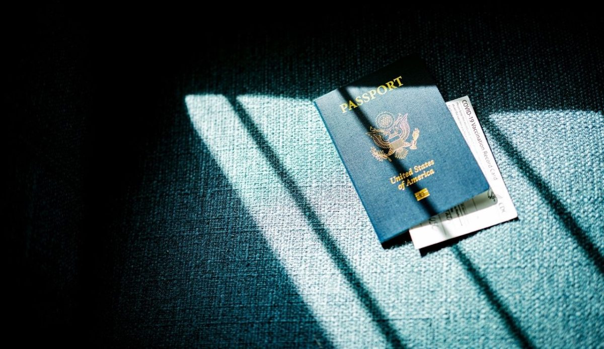 U.S. passport placed on a textured surface with a COVID-19 vaccination record card partly visible underneath
