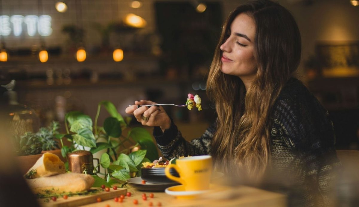 Woman enjoying a meal in a cozy restaurant with a yellow coffee cup on the table
