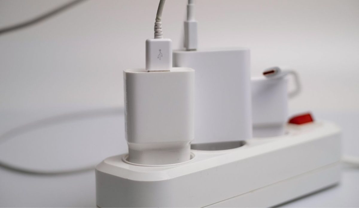 Close up of multiple USB chargers plugged into a white power strip with red switch
