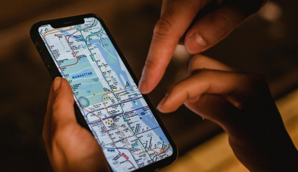 9 Travel Habits Quietly Changing How People Explore 1 Person holding a smartphone showing a subway map of Manhattan while another hand points at the screen