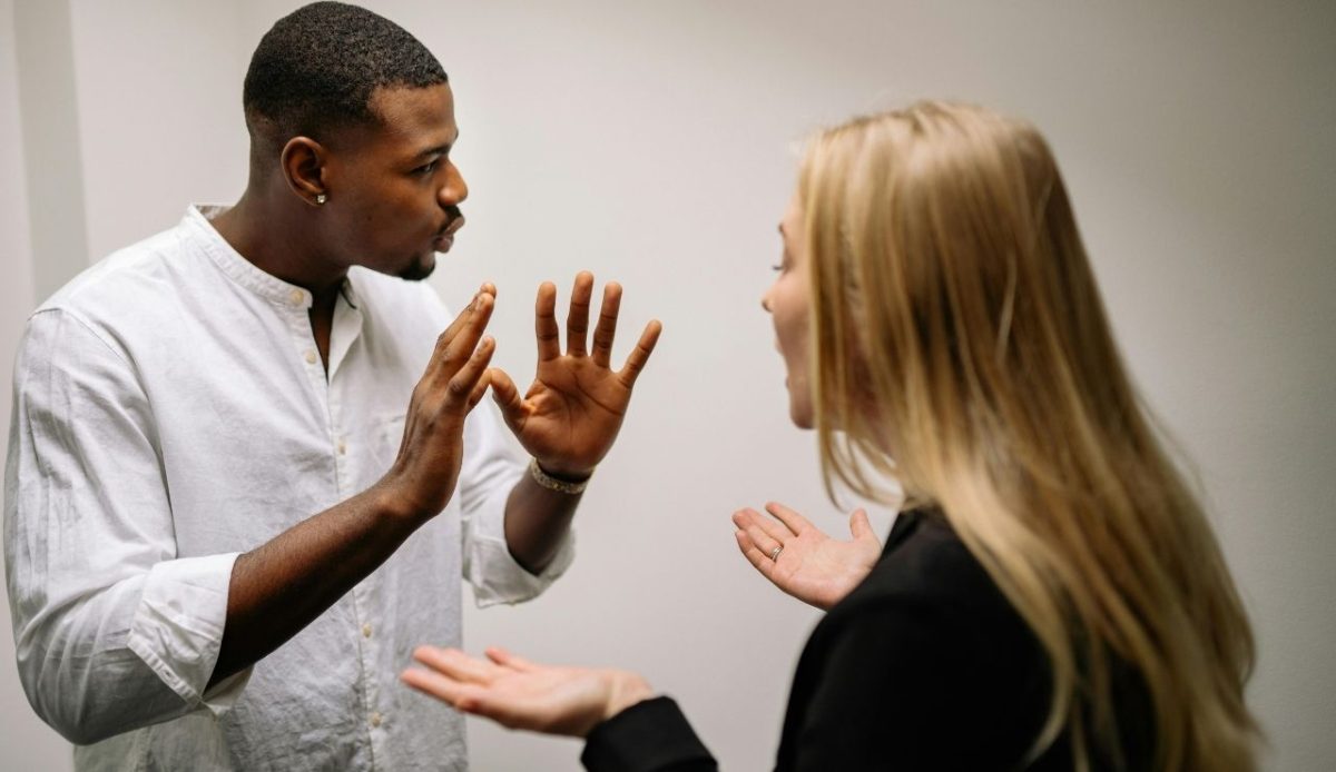 Man and woman having a heated conversation with expressive hand gestures indoors
