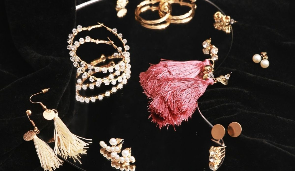 Assorted earrings including hoops, pearl studs, and tassel designs displayed on a black fabric background
