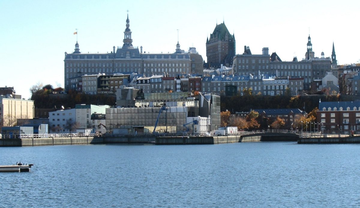 View of Quebec's Old Port, with historic buildings on a hill and a calm waterfront 