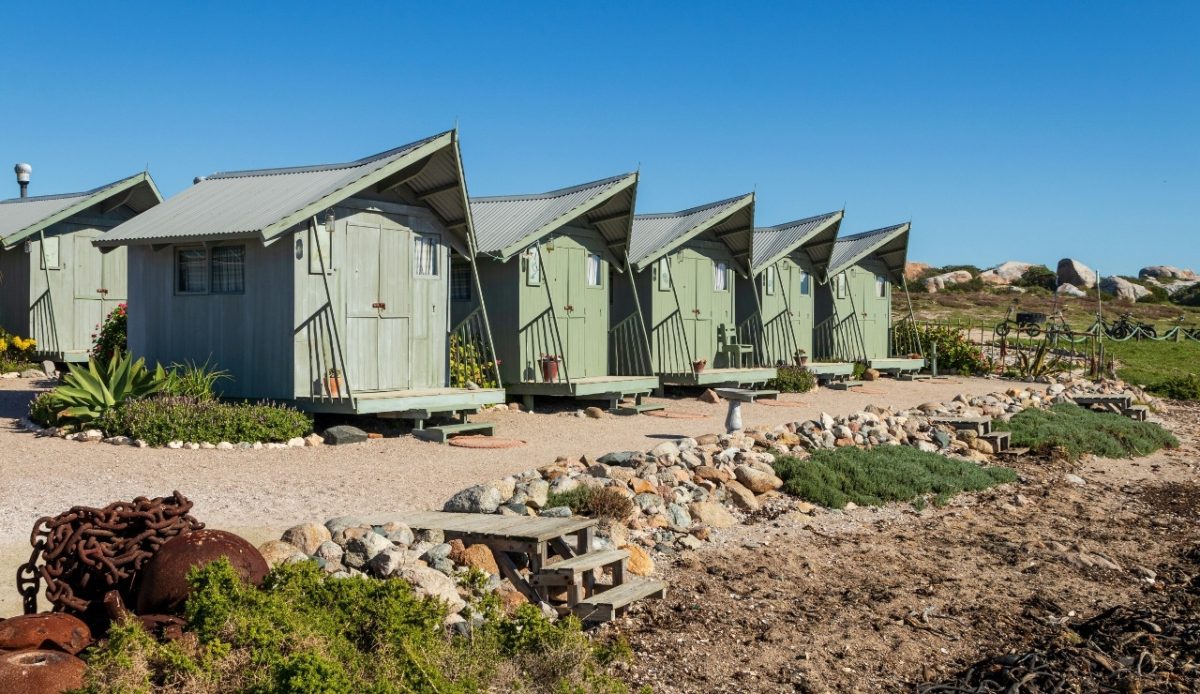 15 Small Towns in South Africa Travelers Should Visit Now 4 Row of small green cabins near the beach in Paternoster, Western Cape, South Africa