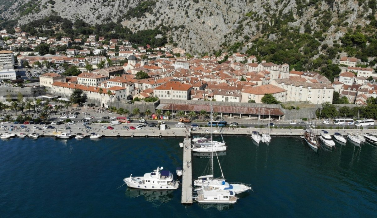 Aerial view of Kotor, Montenegro, with boats docked at the harbor and mountains in the background 