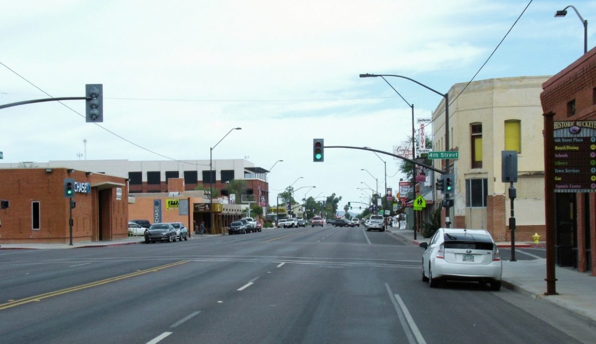 10 Arizona Cities Retirees Often Avoid Living In 3 Buckeye, Arizona Downtown view with street signs and businesses along onroe Ave