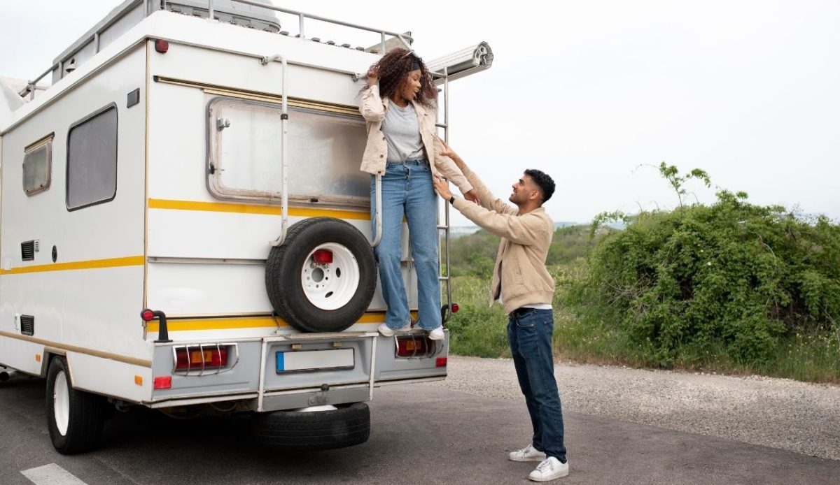 9 Reasons RVs Are Becoming America’s New Vacation Homes 9 Couple enjoying a road trip beside their RV with the woman climbing down the back ladder