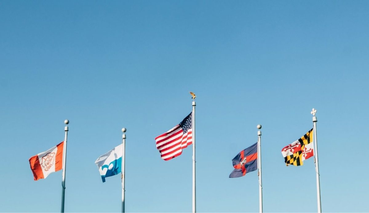 American and state flags waving under clear blue sky