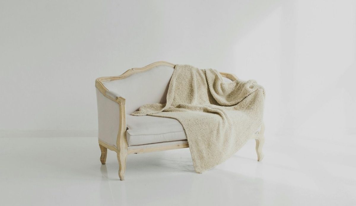 12 Annoying Things Guests Do At Hotels Without Realizing It 5 Beige throw blanket on vintage sofa in bright room