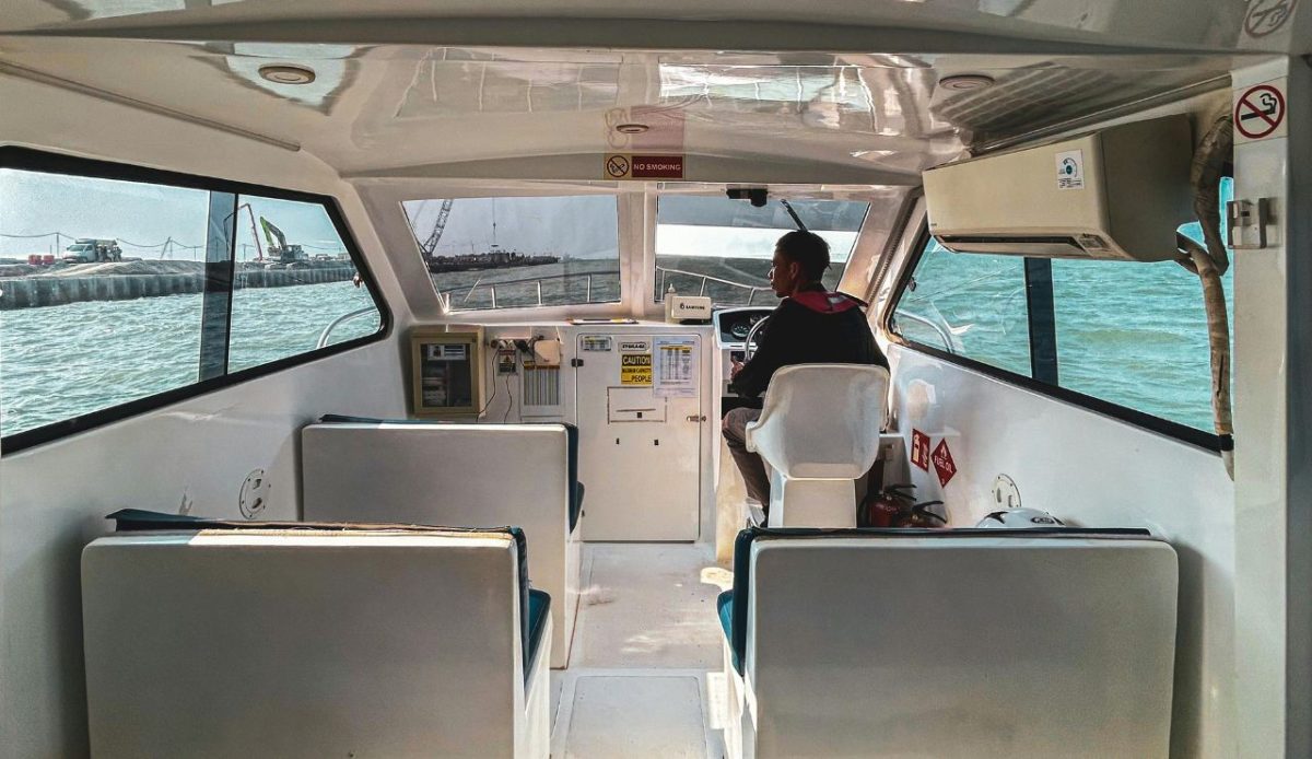 Boat captain steering vessel on calm sea near harbor