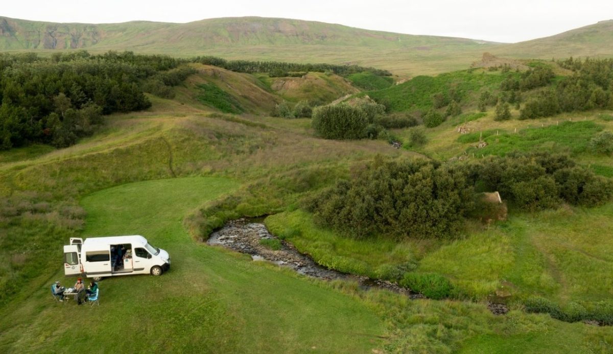 9 Reasons RVs Are Becoming America’s New Vacation Homes 8 Camper van parked beside a small stream in a lush green valley