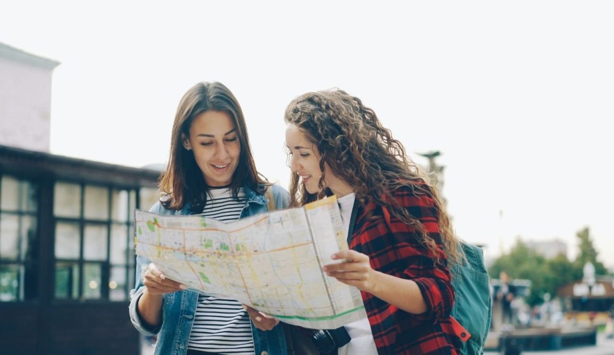 Small Michigan Town Near Ann Arbor Offers Dining, Shopping and Outdoor Fun 6 Cheerful young women are looking at map and talking standing together discussing the right direction