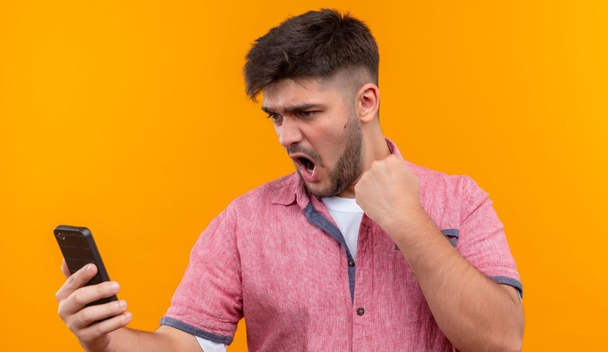 12 Annoying Things Guests Do At Hotels Without Realizing It 1 Excited man celebrating while looking at phone