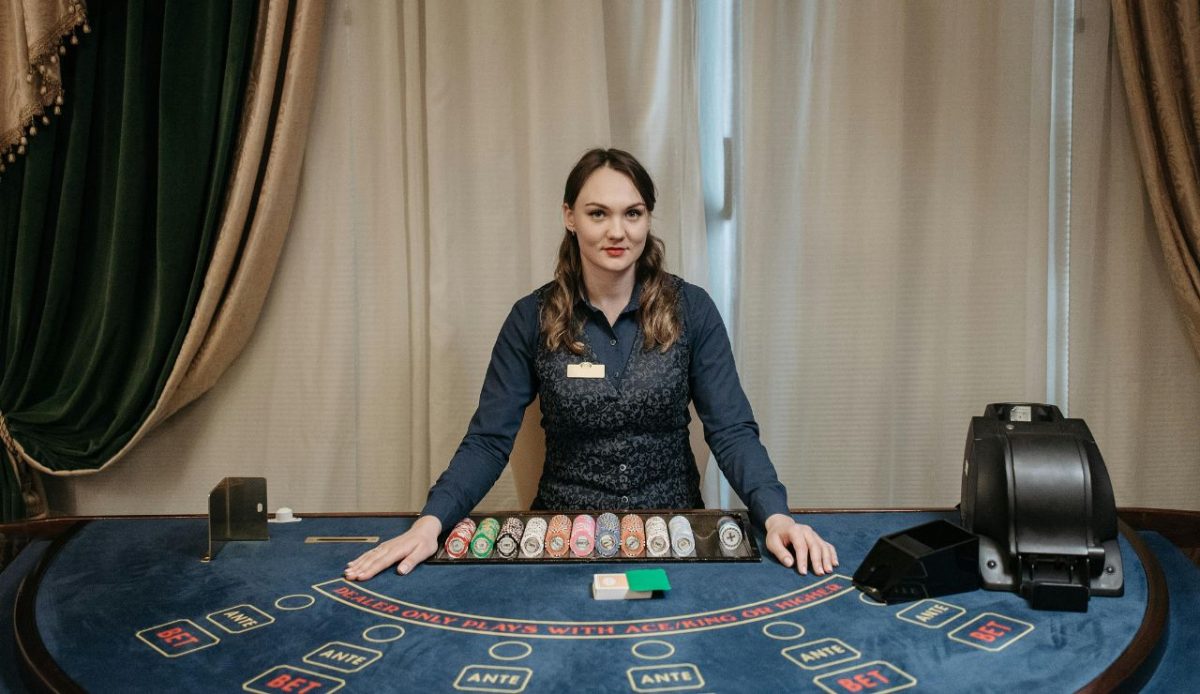 Female casino dealer standing behind poker table