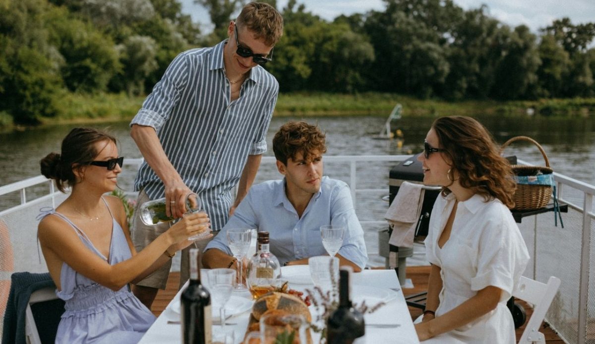Friends enjoying a riverside lunch outdoors on a sunny day