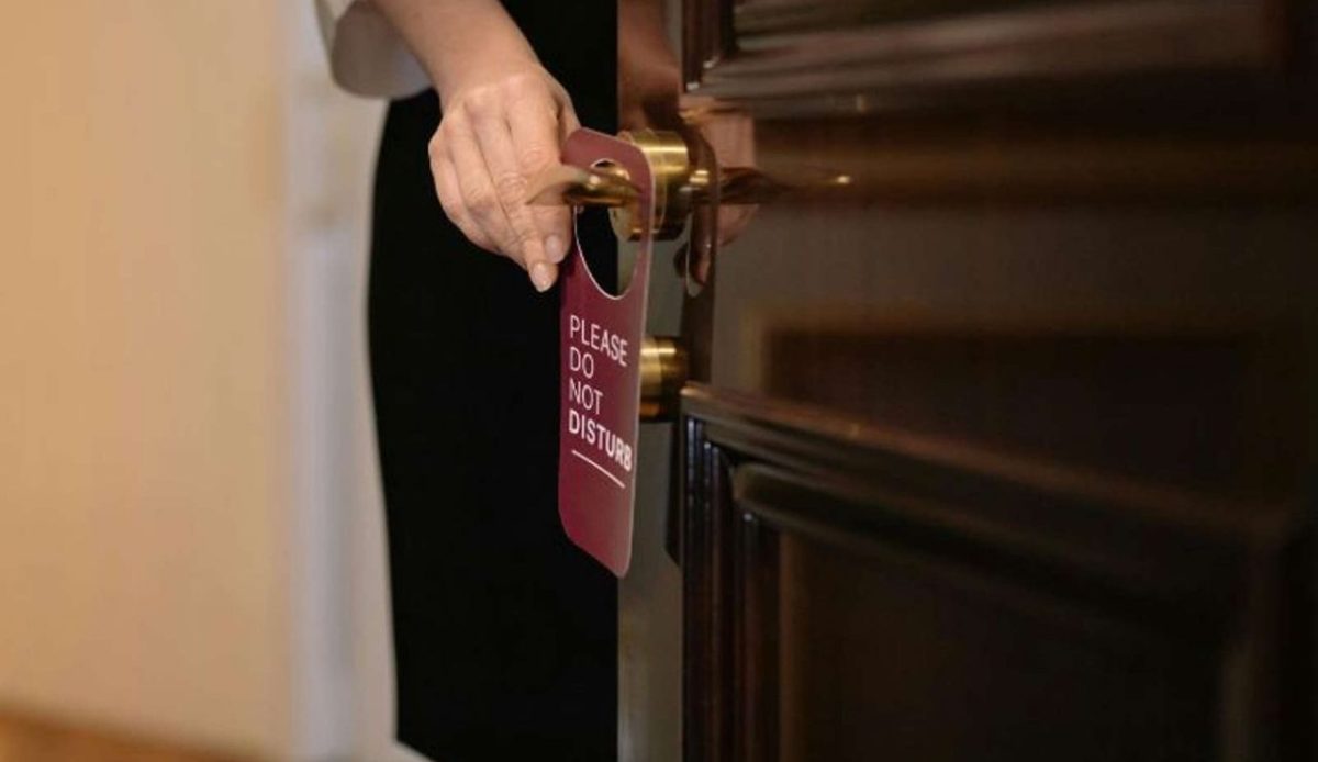 12 Annoying Things Guests Do At Hotels Without Realizing It 7 Hand placing a do not disturb sign on hotel door handle