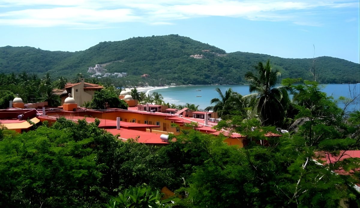 Zihuatanejo, Guerrero A view over Playa La Ropa with red-roofed buildings and lush greenery 