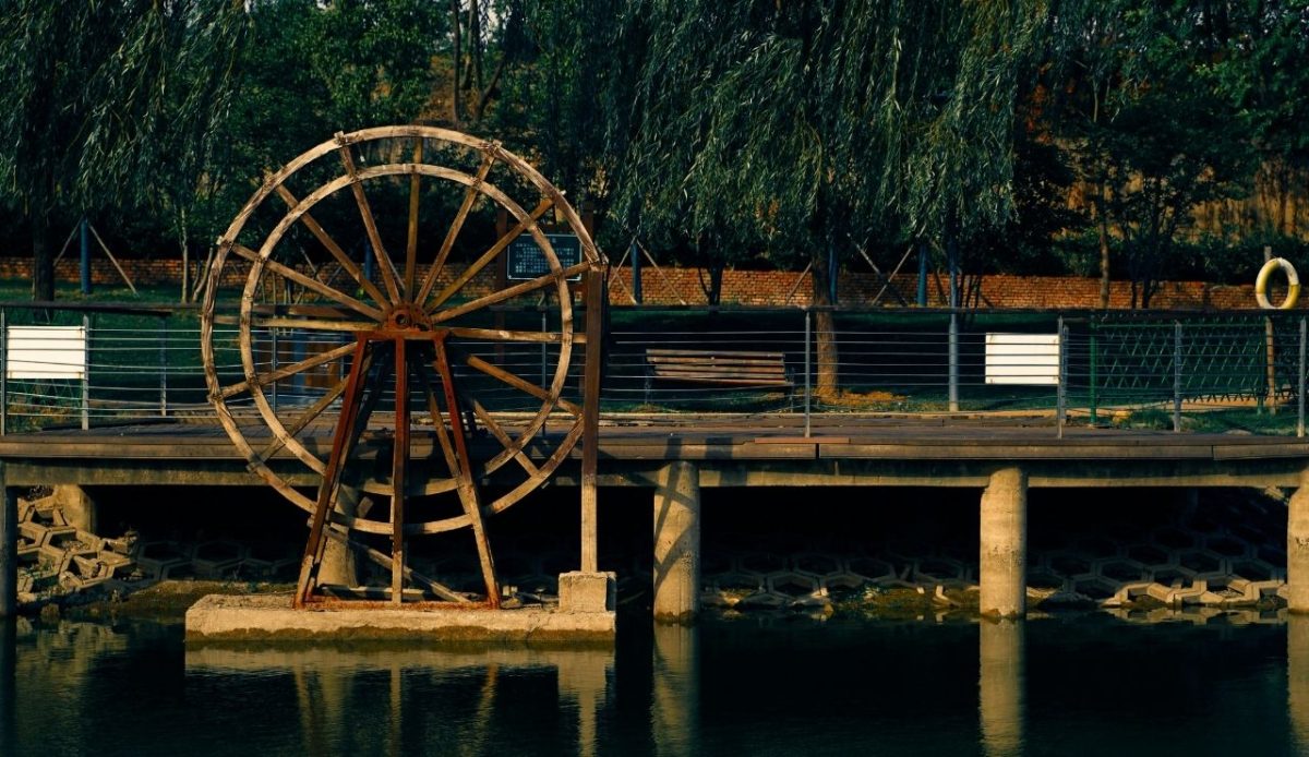 Inside the Abandoned Disney Resort With a Complicated Past 3 Old wooden water wheel by a riverside pier surrounded by trees