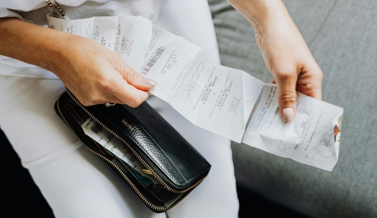 Person checking receipts beside a black wallet