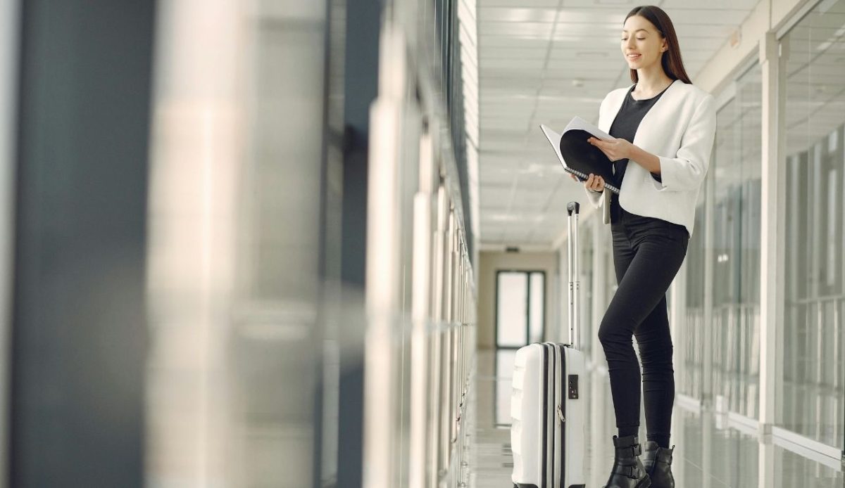 10 Things Never to Wear on a Plane and 6 Smarter Picks Instead 11 Smiling woman with notebook and suitcase in airport
