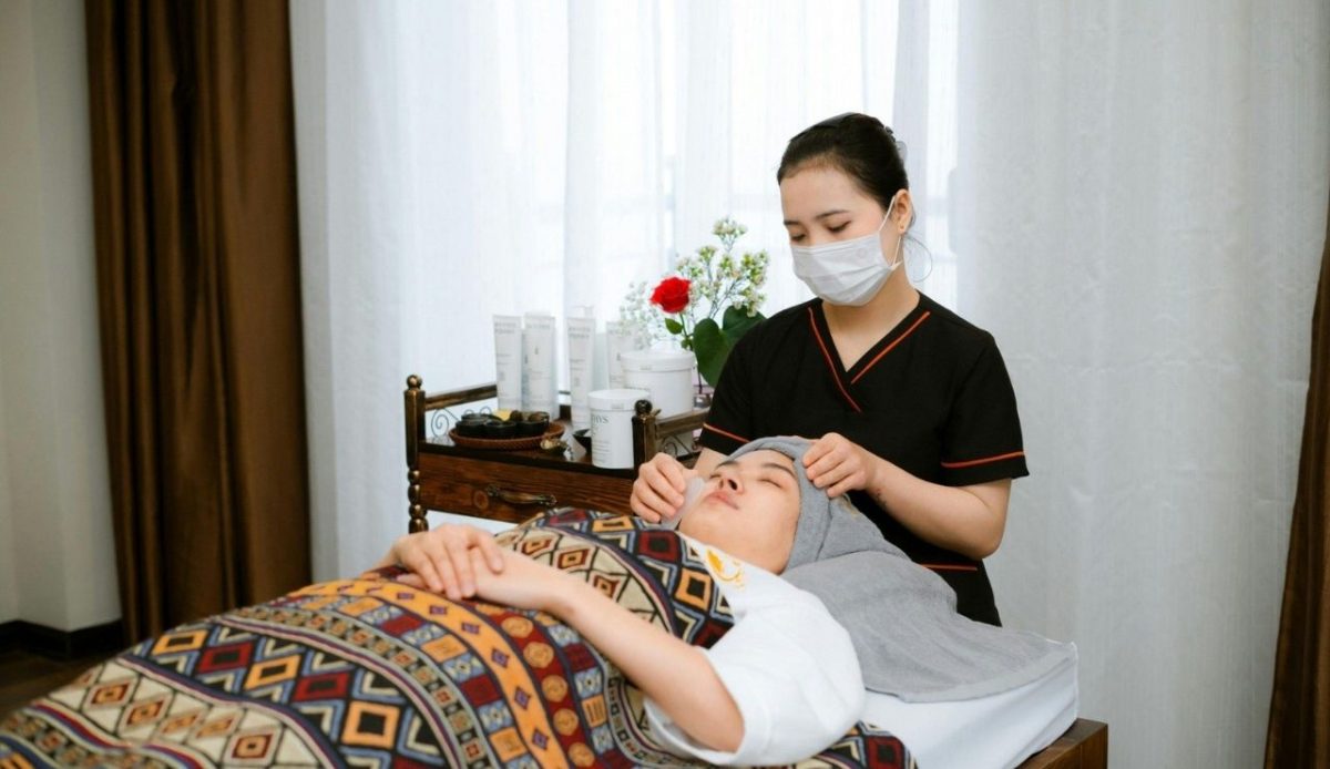 Spa therapist wearing mask giving facial treatment to a client