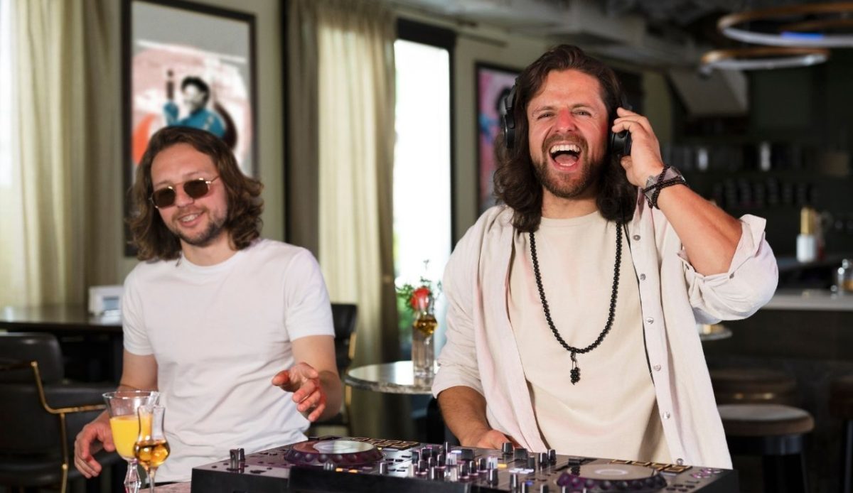 Two male DJs performing with mixing console in a lively bar