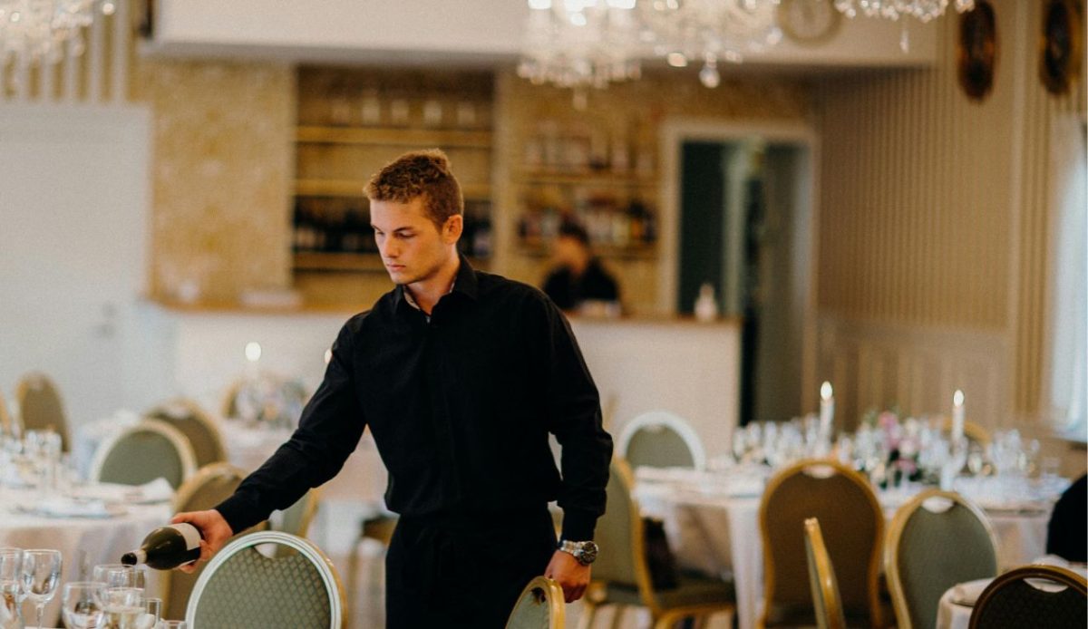 Waiter in black uniform pouring wine at a fine dining restaurant