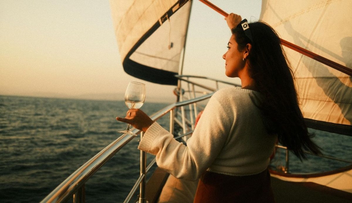 14 Best Airbnb Experiences Around the World Worth Trying 9 Woman holding a wine glass while sailing on a boat at sunset