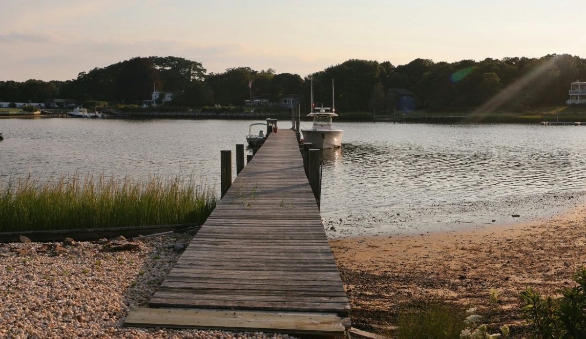 8 Peaceful Northeast Beach Towns to Visit and 4 Better Skipped 6 Wooden dock leading to moored boats on a calm river at sunset,Hampton bay, New Yorkrk, USA