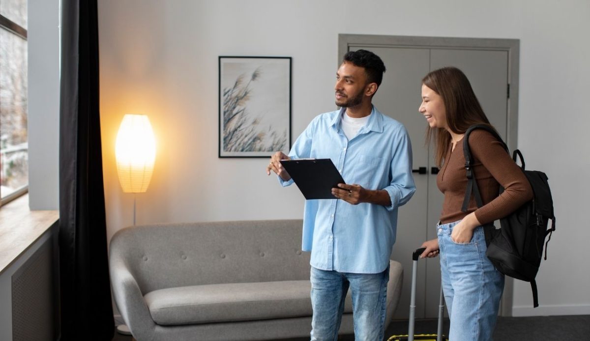 What To Know About Airbnb Experiences Before You Book 5 Guest with luggage talking to a host holding a clipboard inside a modern apartment
