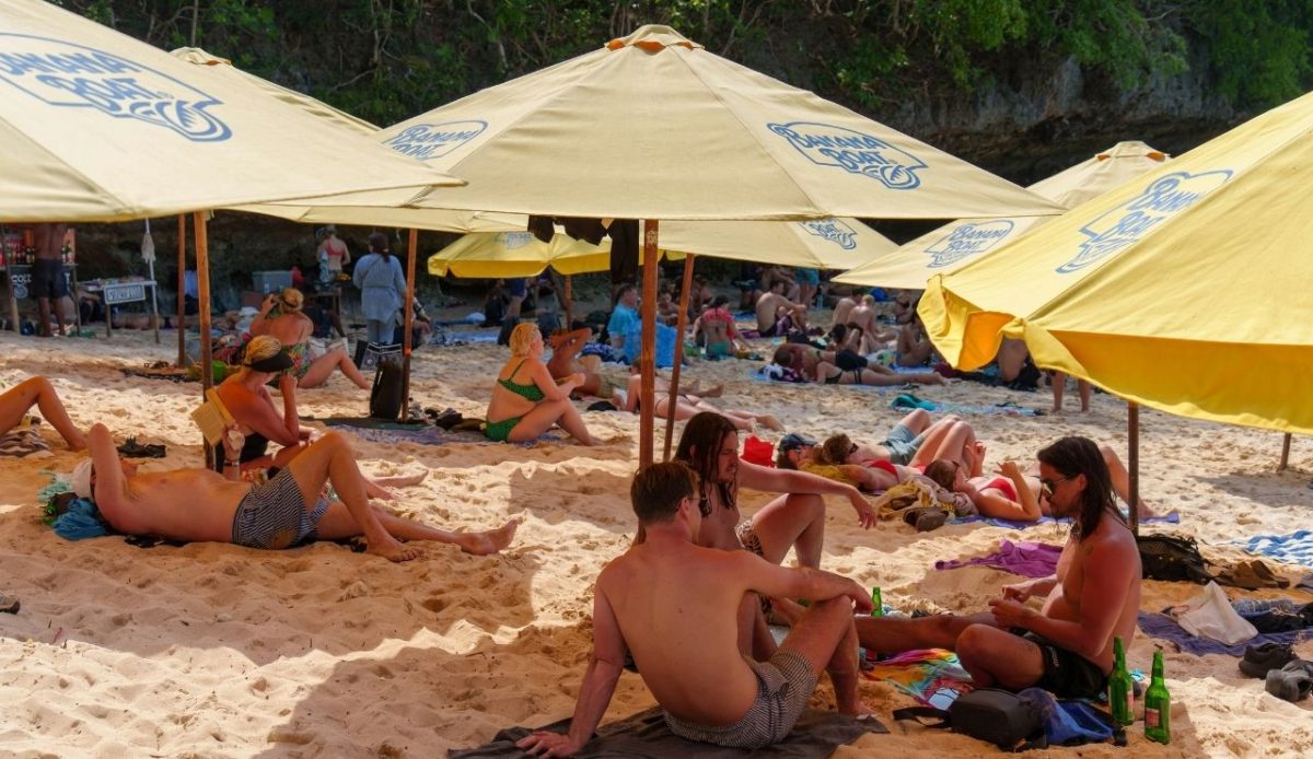 crowded beach with yellow umbrellas and people relaxing on the sand