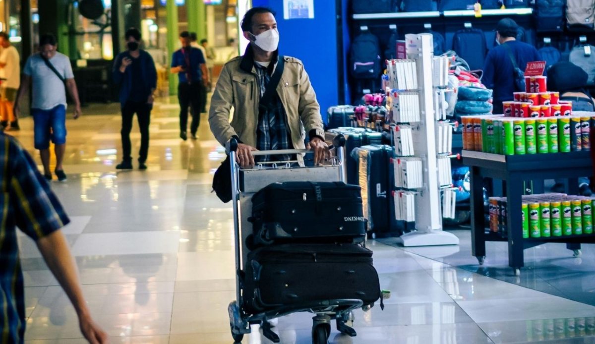 Man Walking on Airport Corridor with luggage loaded on trolly               