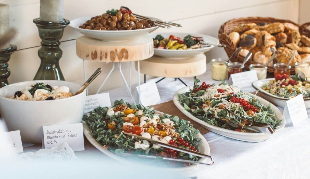 Assorted salads, potatoes, and bread displayed on a buffet table with mixed ingredients in various bowls and trays                    