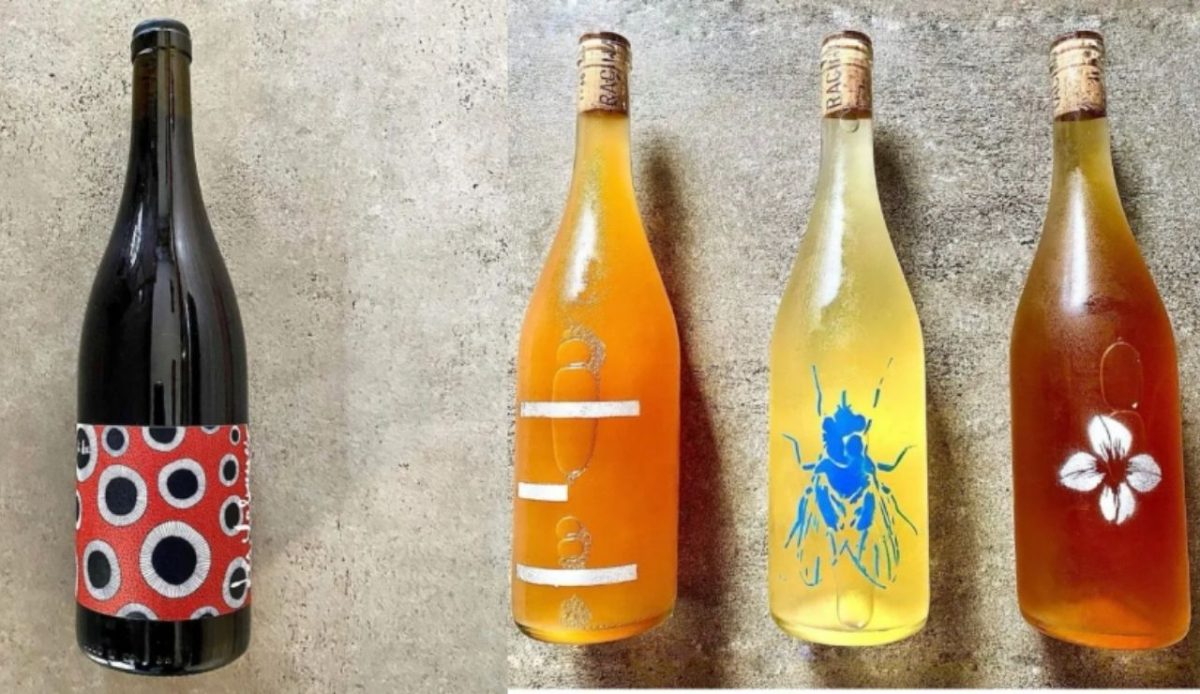 Assorted wine bottles with colorful artistic labels arranged on a concrete surface      