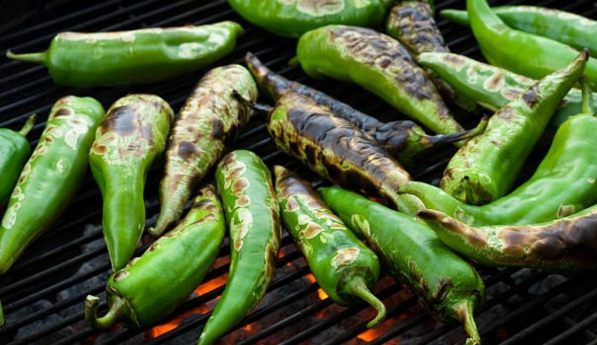Fresh anaheim chili peppers being roasted over a charcoal fire            