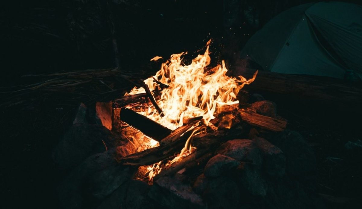 Large campfire burning at night with no one nearby, showing the risk of unattended fires           