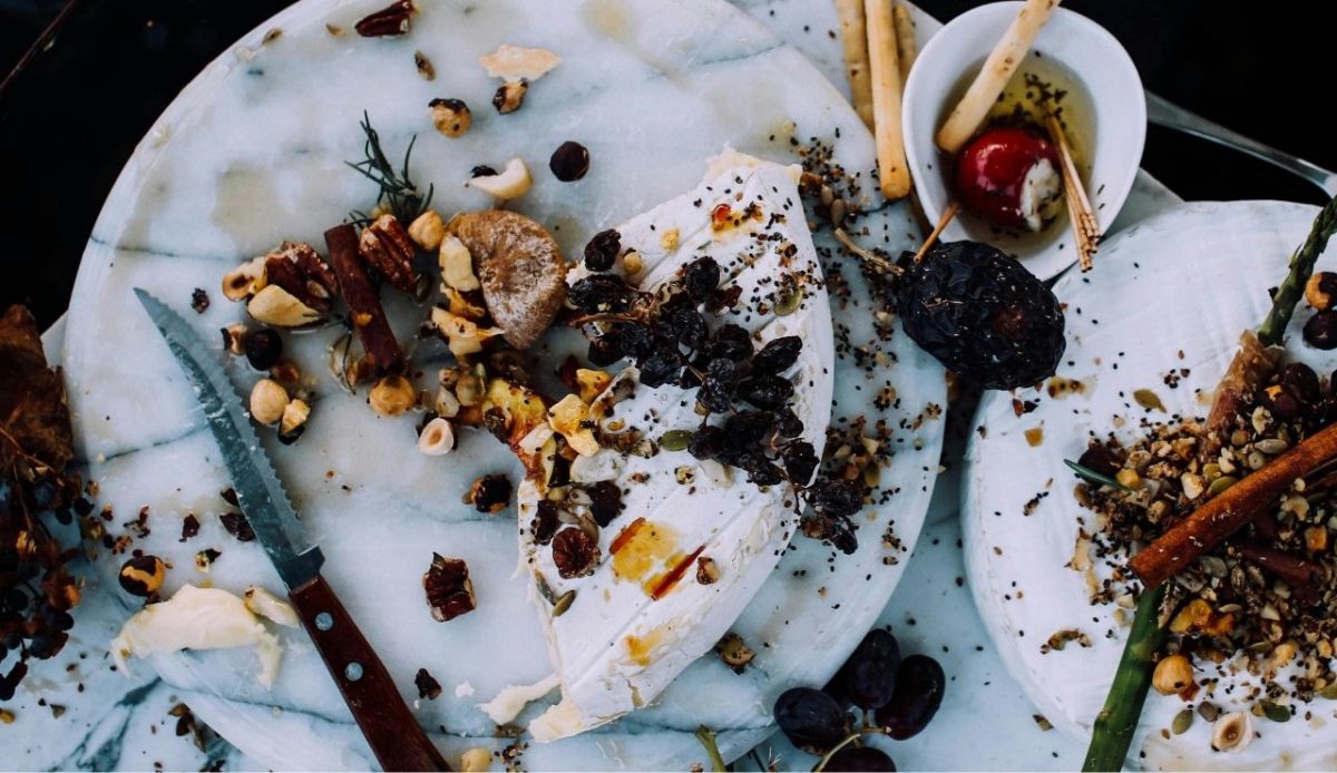 Leftover food waste with cheese, nuts, and fruit on marble plates