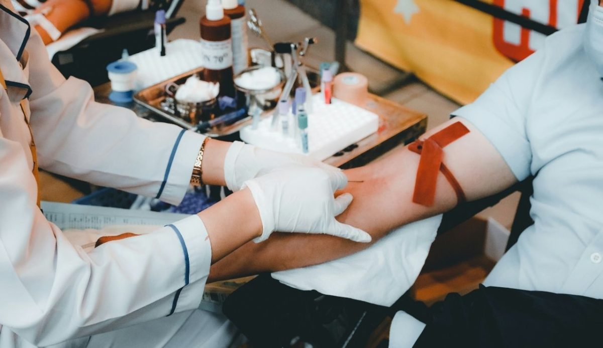 Nurse drawing blood from a patient’s arm during a medical procedure indoors                  