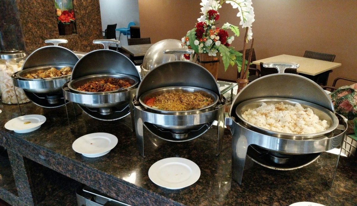 Open buffet chafing dishes with hot food sitting out on a serving counter