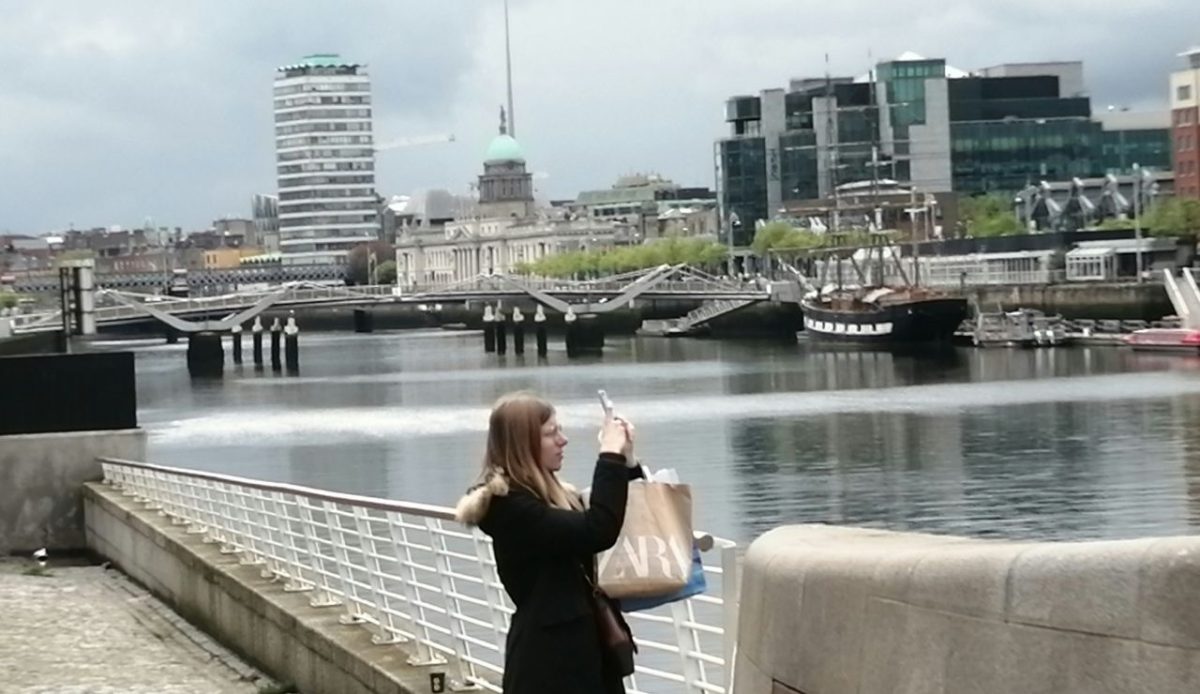 Person taking photo along River Liffey near Samuel Beckett Bridge, Dublin Ireland          