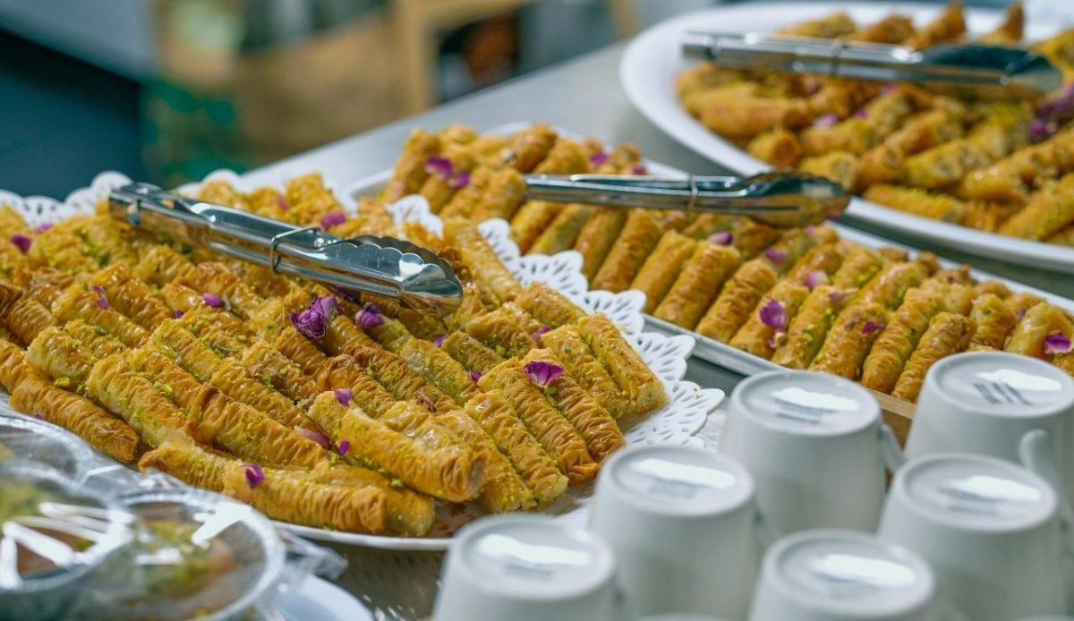 Shared metal tongs resting on buffet trays filled with pastries