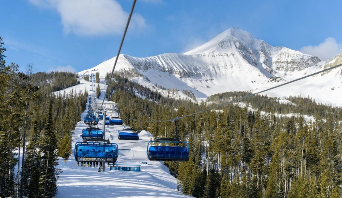 Ski lift with blue gondolas at Big Sky Resort in Montana, snowy mountain in background