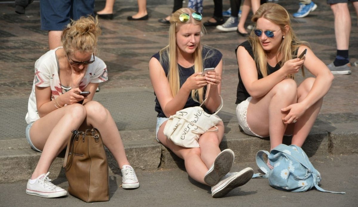 Three young blond women sitting on the street in shorts  Prague, Czechia         