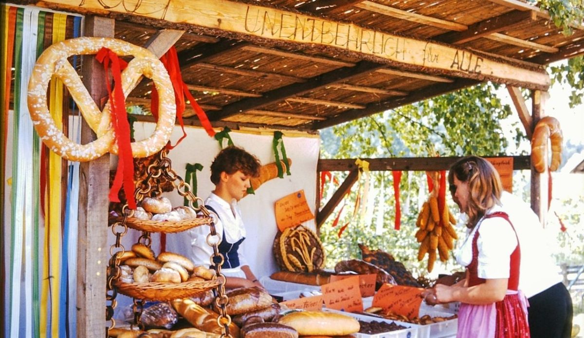 Traditional bread stall at a German festival with vendors in regional attire                       