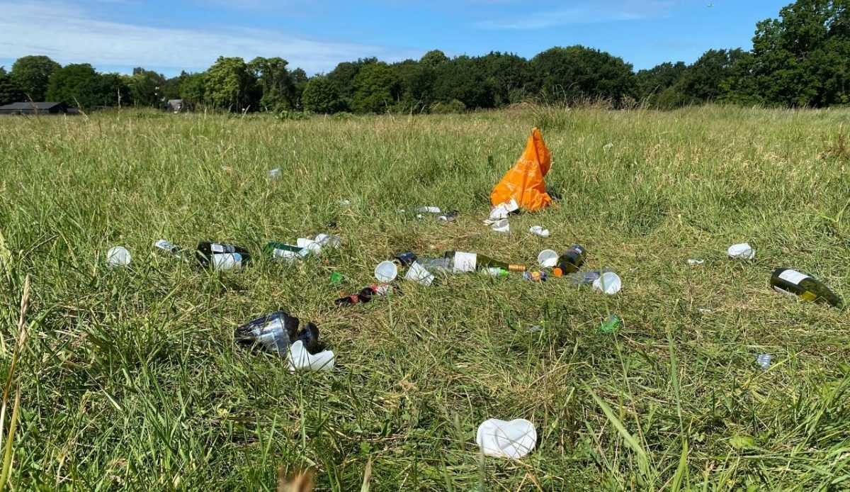 Trash and bottles left scattered on an open grassy field           